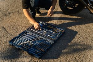 Seorang teknisi sedang melakukan Skill Diagnosa Motor Matic dan Bebek di Jurusan TSM menggunakan alat khusus di bengkel.
